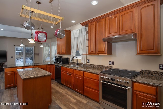 kitchen featuring appliances with stainless steel finishes, kitchen peninsula, dark wood-type flooring, a kitchen island, and decorative light fixtures