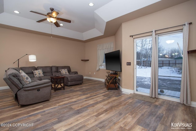 living room featuring a raised ceiling, ceiling fan, and dark hardwood / wood-style floors