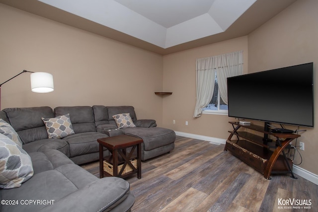 living room with a tray ceiling and dark hardwood / wood-style floors