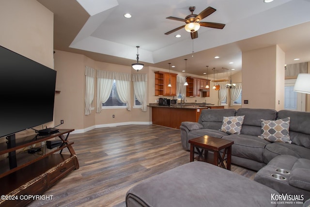 living room featuring ceiling fan, a tray ceiling, and dark hardwood / wood-style floors