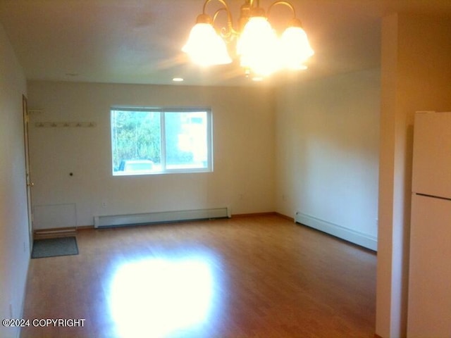 unfurnished room featuring an inviting chandelier and a baseboard heating unit