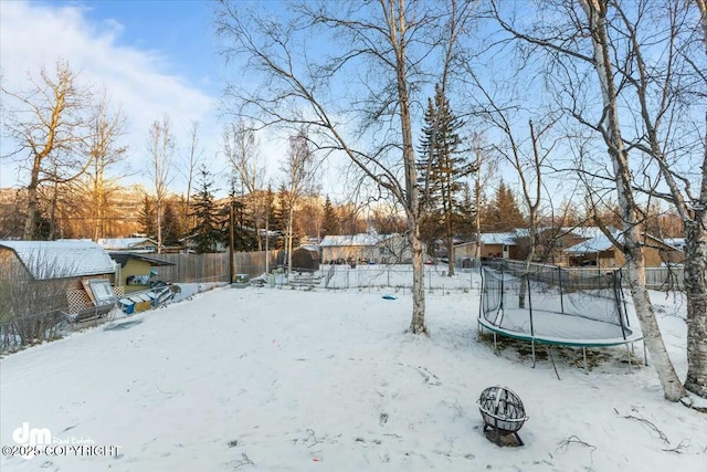 yard layered in snow with a trampoline and a fire pit