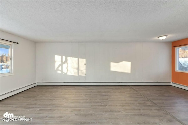 empty room with baseboard heating, light hardwood / wood-style floors, and a textured ceiling