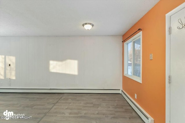 unfurnished room featuring a baseboard radiator and hardwood / wood-style floors