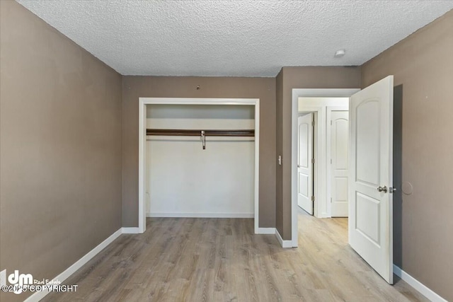 unfurnished bedroom featuring light hardwood / wood-style flooring, a textured ceiling, and a closet