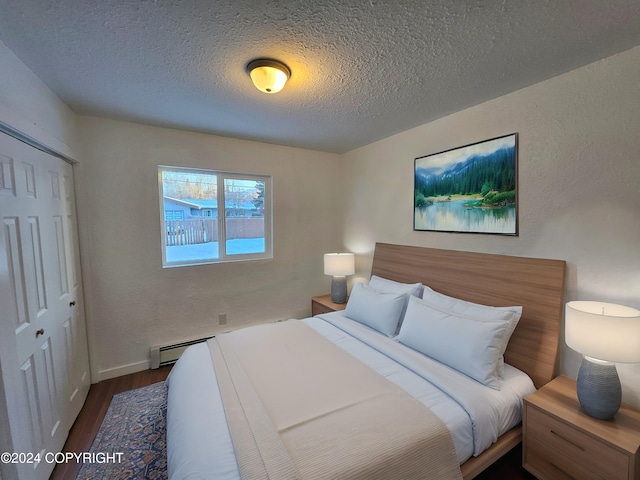 bedroom featuring a textured ceiling, dark wood-type flooring, a baseboard radiator, and a closet