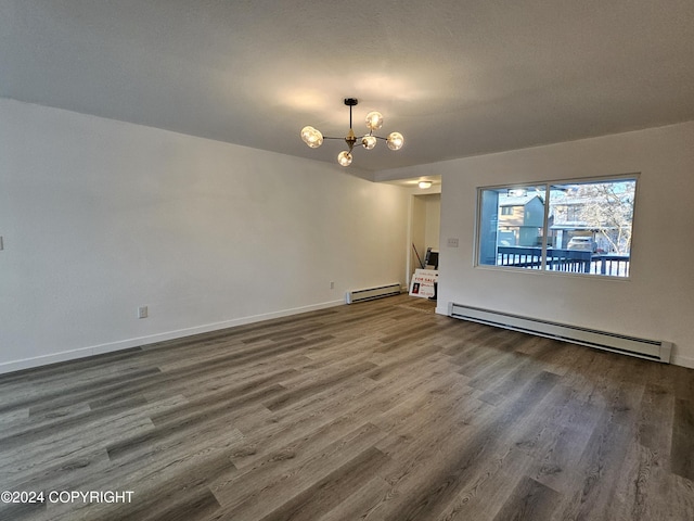 spare room featuring wood-type flooring, a baseboard radiator, and a notable chandelier