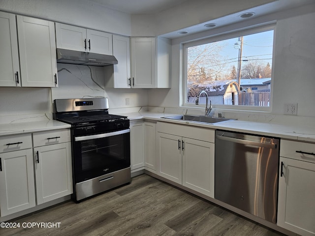 kitchen with appliances with stainless steel finishes, white cabinetry, dark wood-type flooring, and sink