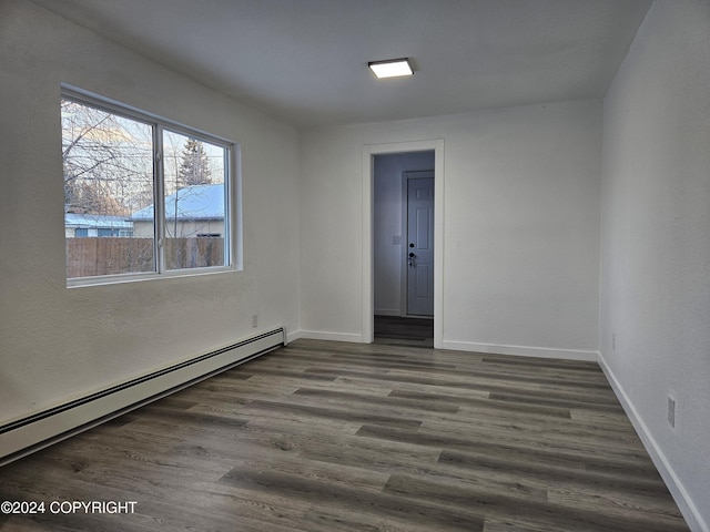 spare room featuring baseboard heating and dark hardwood / wood-style floors