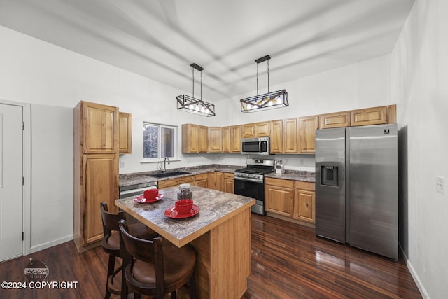 kitchen with sink, hanging light fixtures, stainless steel appliances, a kitchen breakfast bar, and a kitchen island