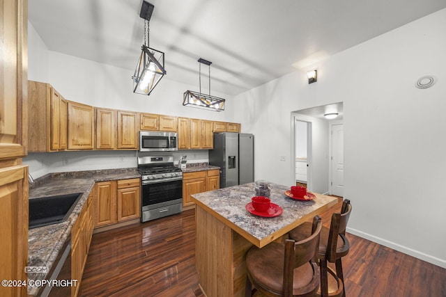 kitchen featuring stainless steel appliances, dark wood-type flooring, pendant lighting, a kitchen island, and a breakfast bar area