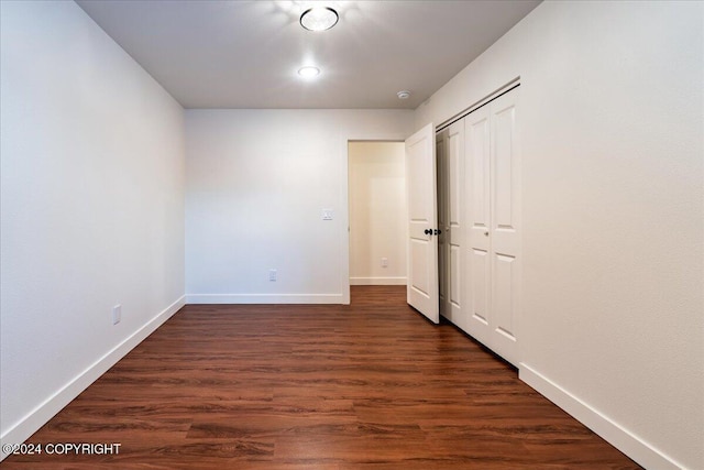 unfurnished bedroom featuring a closet and dark wood-type flooring