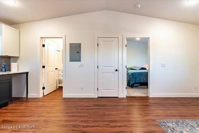 interior space featuring wood-type flooring, connected bathroom, electric panel, and lofted ceiling