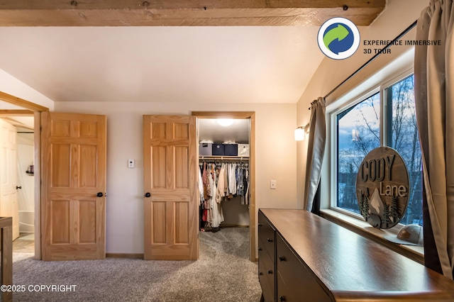 bedroom with a spacious closet, a closet, light colored carpet, and lofted ceiling with beams