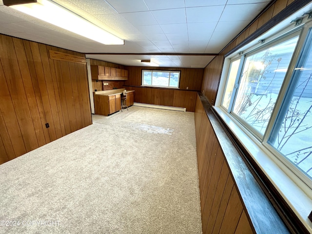 interior space with wooden walls, baseboard heating, and light carpet