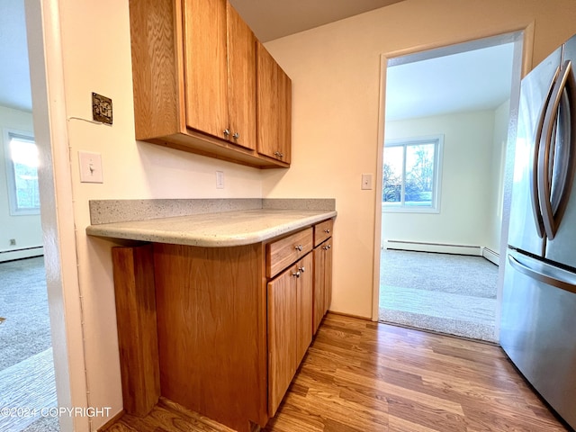 kitchen featuring light hardwood / wood-style flooring, a baseboard radiator, and stainless steel fridge