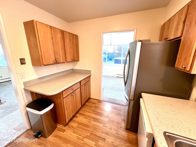 kitchen with sink, light hardwood / wood-style flooring, a baseboard heating unit, and stainless steel refrigerator