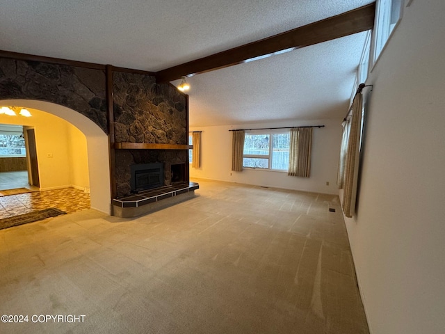 unfurnished living room featuring arched walkways, lofted ceiling with beams, carpet, a textured ceiling, and a stone fireplace