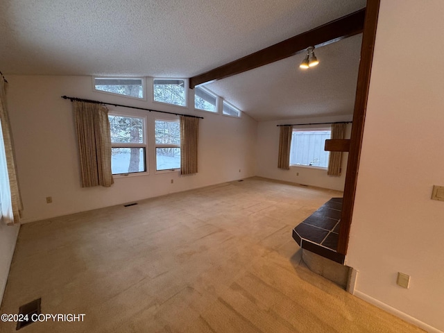 empty room with light carpet, a textured ceiling, visible vents, and vaulted ceiling with beams