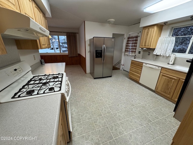 kitchen featuring white appliances, under cabinet range hood, light countertops, and a sink