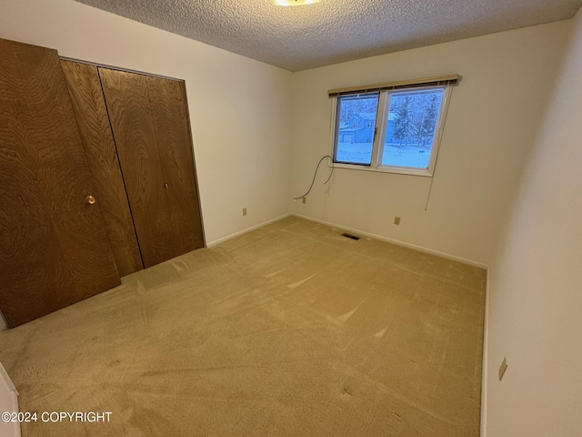 unfurnished bedroom with carpet floors, a closet, visible vents, and a textured ceiling