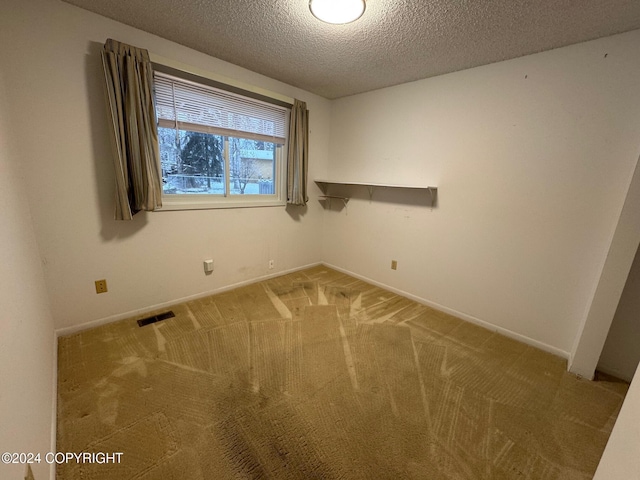 spare room with carpet, visible vents, a textured ceiling, and baseboards