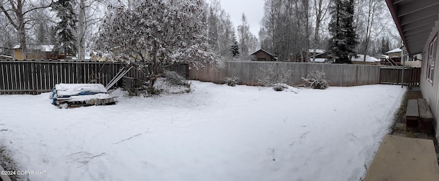 snowy yard featuring a fenced backyard