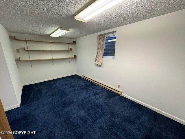 finished basement featuring a baseboard radiator, baseboards, a textured ceiling, and dark colored carpet