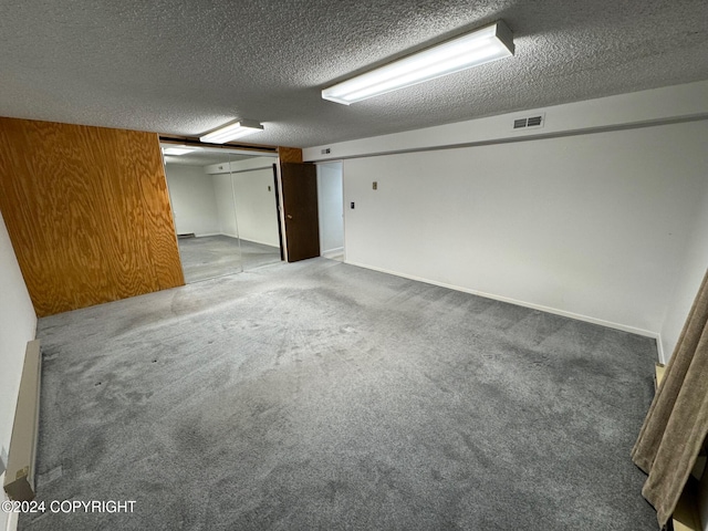 finished below grade area with a textured ceiling, carpet floors, and visible vents