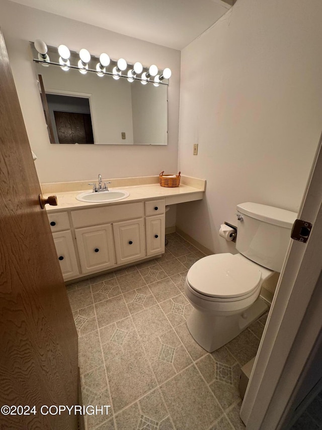 half bathroom with toilet, vanity, and tile patterned floors