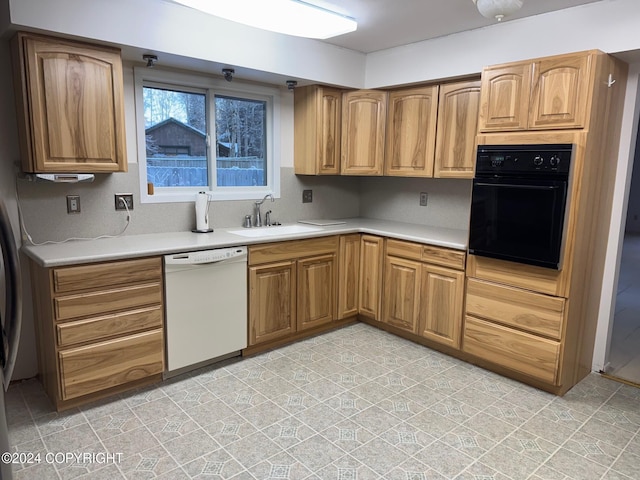 kitchen featuring brown cabinets, light countertops, a sink, black oven, and dishwasher