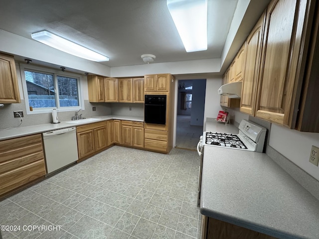 kitchen with under cabinet range hood, white appliances, a sink, light countertops, and brown cabinetry