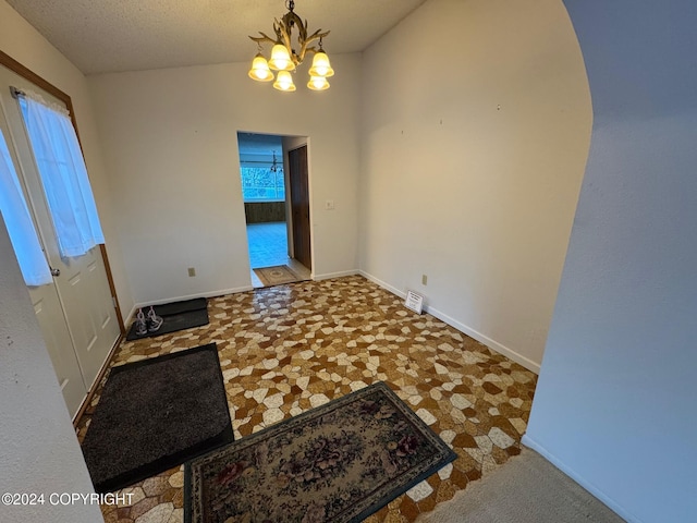 interior space featuring a chandelier, vaulted ceiling, visible vents, and baseboards