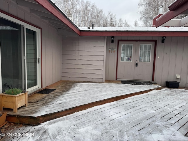 snow covered property entrance with french doors and a wooden deck