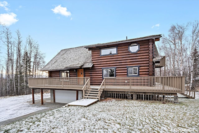 snow covered back of property featuring a wooden deck and a garage