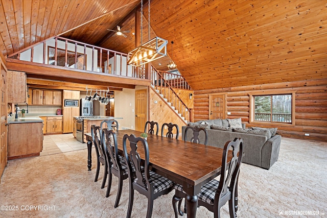 carpeted dining area featuring high vaulted ceiling, ceiling fan, rustic walls, and wooden ceiling