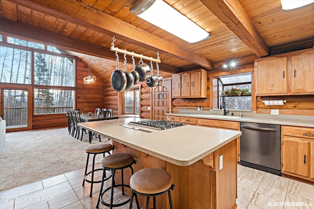 kitchen with appliances with stainless steel finishes, log walls, a kitchen island, beamed ceiling, and sink