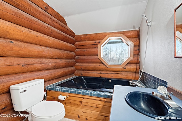 bathroom with sink, toilet, rustic walls, and lofted ceiling