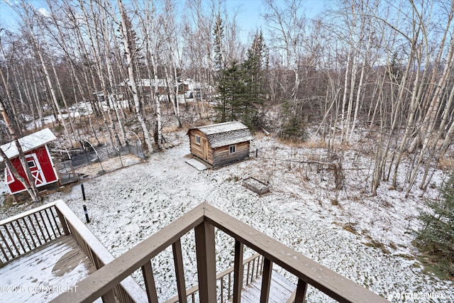 yard covered in snow featuring a wooden deck and a shed