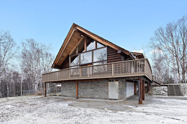 snow covered house featuring a deck and a garage