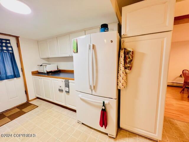 3411 Monashka Bay Rd, Kodiak, AK 99615 - kitchen featuring freestanding refrigerator, white cabinets, light floors, and dark countertops