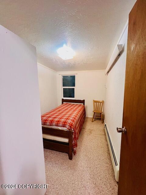 3411 Monashka Bay Rd, Kodiak, AK 99615 - carpeted bedroom with a baseboard radiator and a textured ceiling