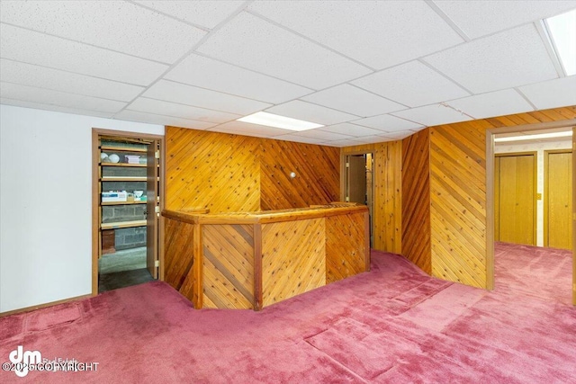 bar with carpet, a paneled ceiling, and wood walls