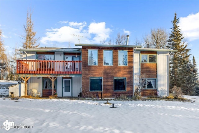 snow covered house with a wooden deck