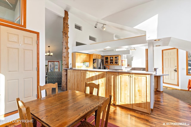 dining room featuring light hardwood / wood-style flooring, high vaulted ceiling, and an inviting chandelier