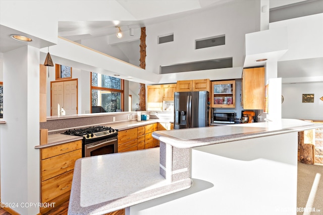 kitchen featuring beamed ceiling, kitchen peninsula, stainless steel appliances, and high vaulted ceiling