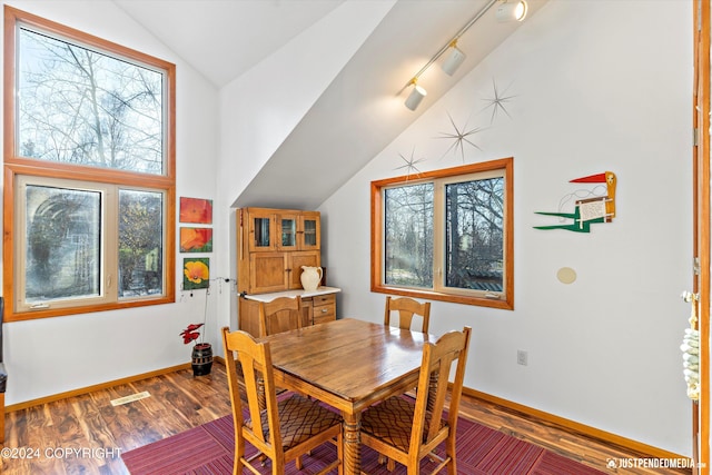 dining area with hardwood / wood-style floors, rail lighting, and vaulted ceiling