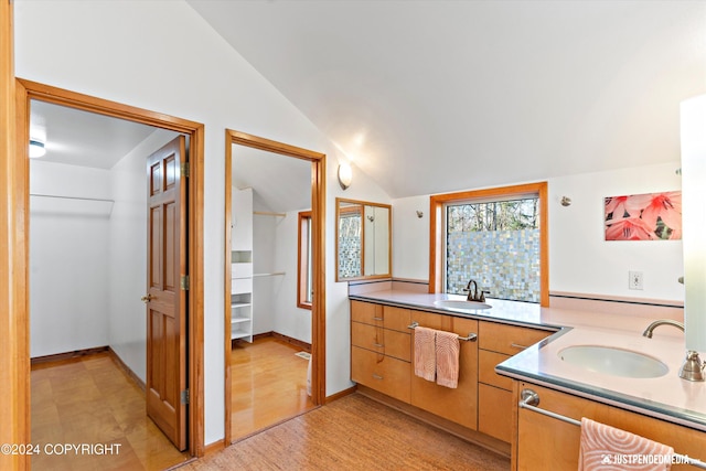 bathroom featuring hardwood / wood-style floors, vanity, and vaulted ceiling