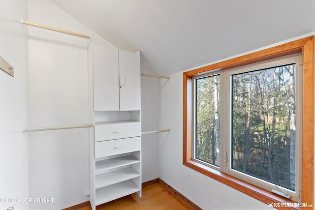 spacious closet with light hardwood / wood-style flooring and vaulted ceiling