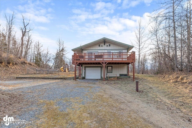 rustic home with a garage, a deck, and dirt driveway